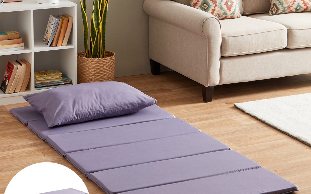 Foldable tri-fold guest mattress opened beside a sofa