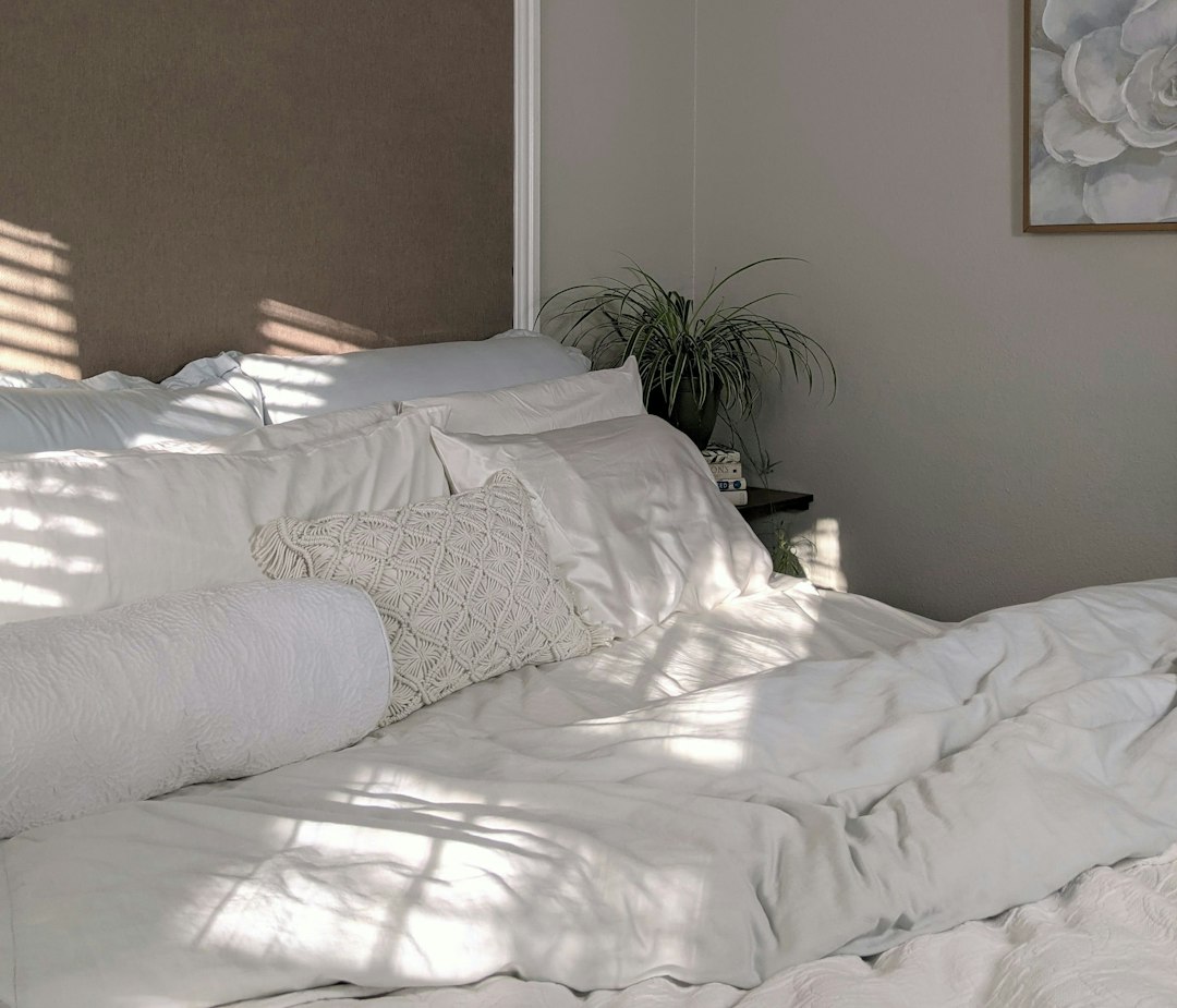 White bedding in a bright bedroom, representing sheets and linens in a regular home-cleaning schedule