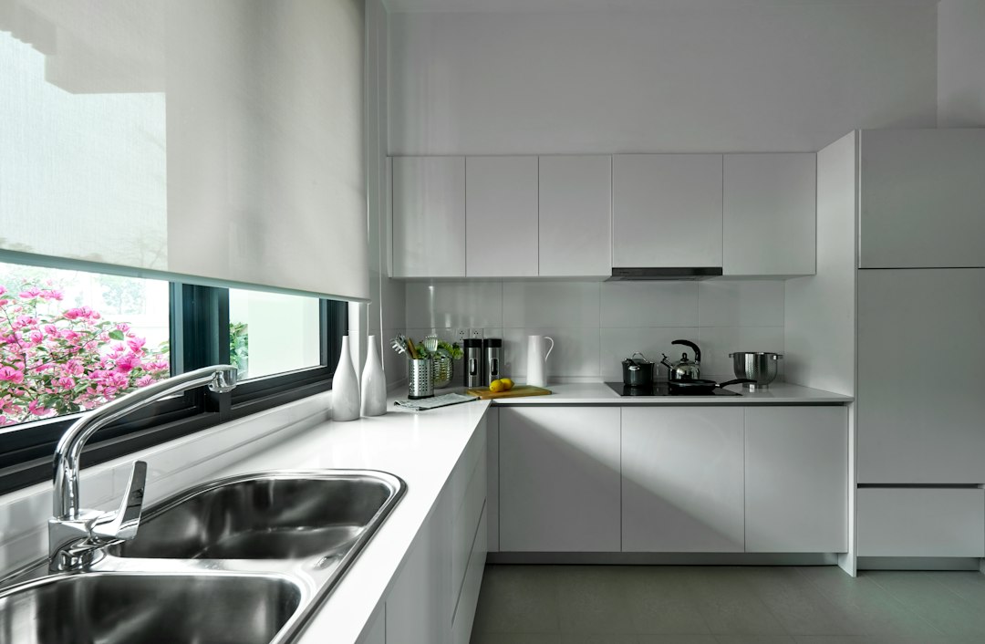 Stainless steel sink by a window in a compact kitchen, illustrating a clear-sink habit for daily kitchen cleaning