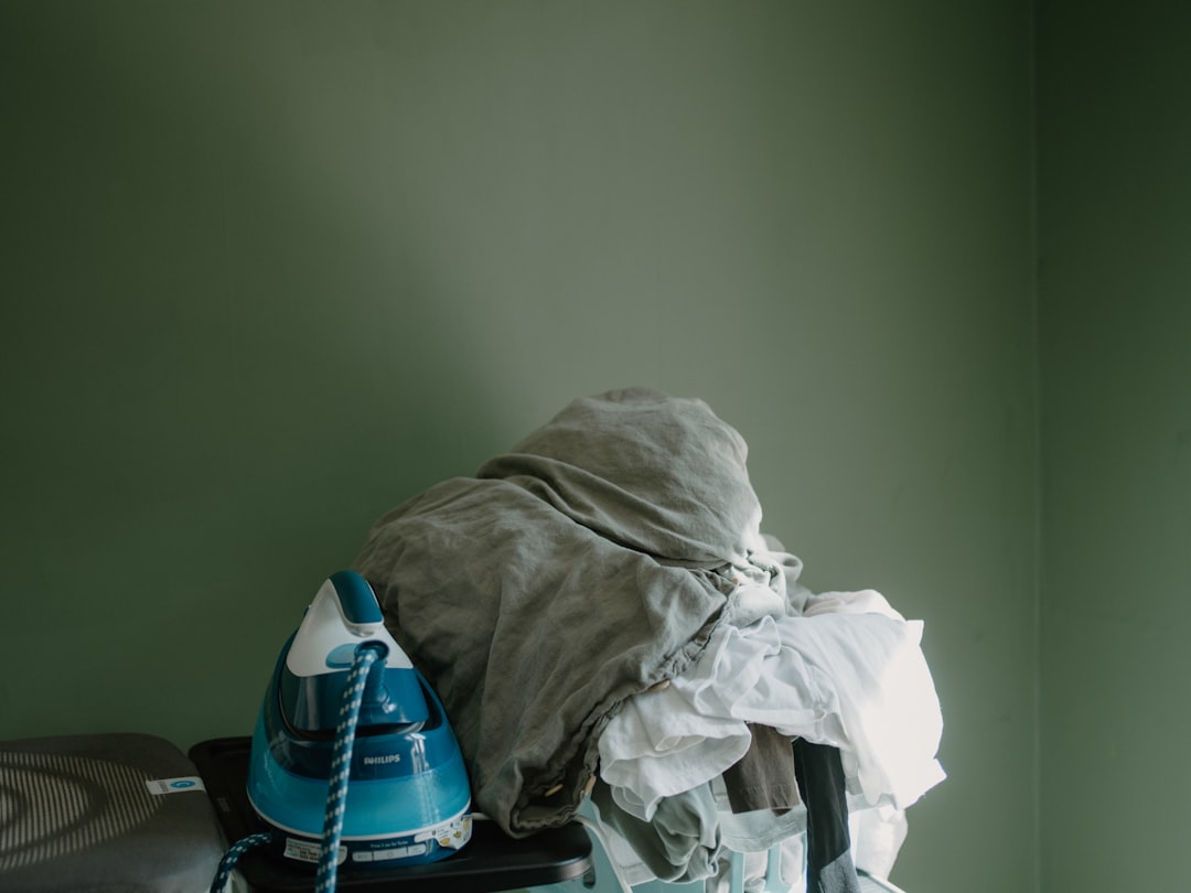 Iron and a pile of clothes on an ironing board, illustrating how extra laundry steps can become a bottleneck