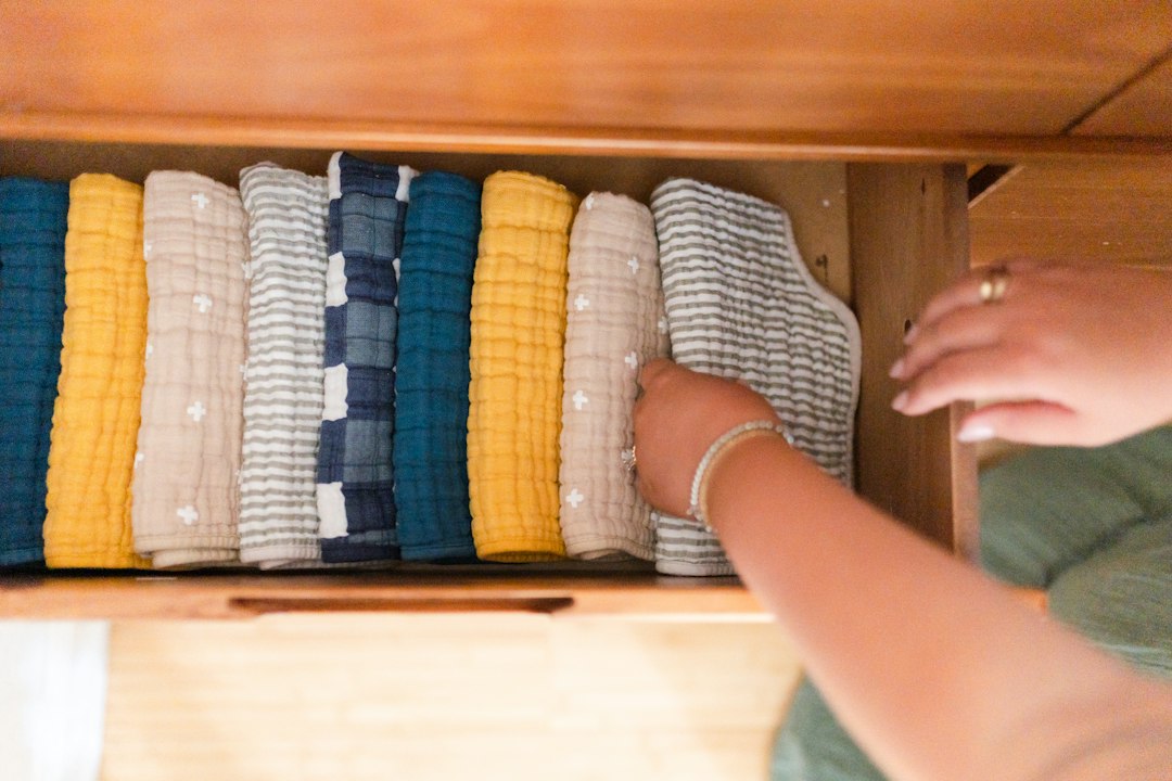 Person placing folded sweaters into a drawer, showing the put-away step that completes the laundry cycle