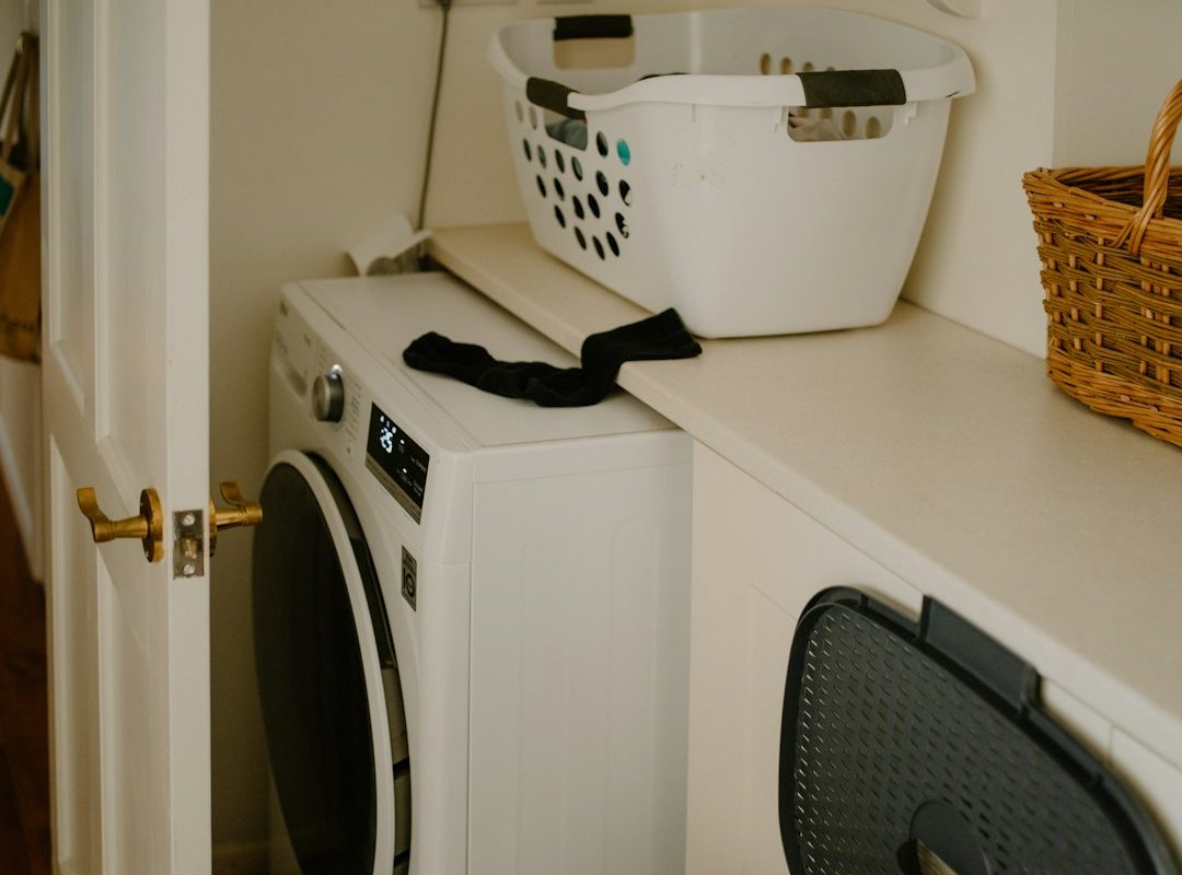 White washing machine with a laundry basket nearby, illustrating a compact everyday laundry setup