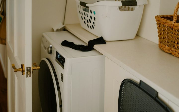 White washing machine with a laundry basket nearby, illustrating a compact everyday laundry setup