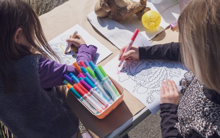 Two children using markers and crayons at a shared table