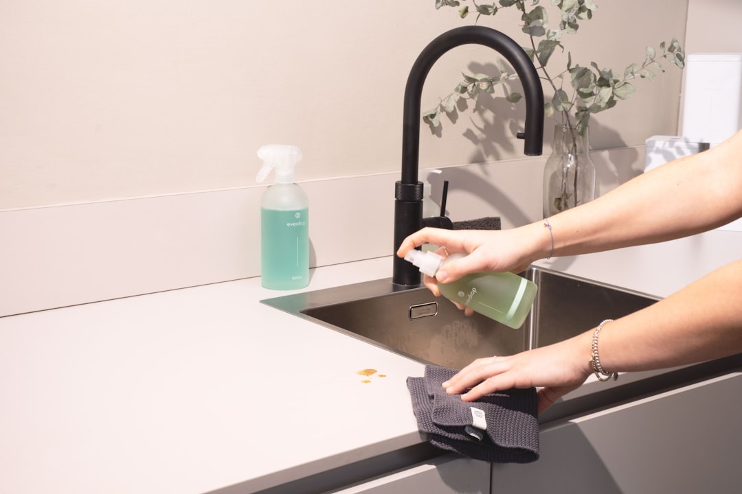 Person wiping around a sink area during a detailed cleaning session