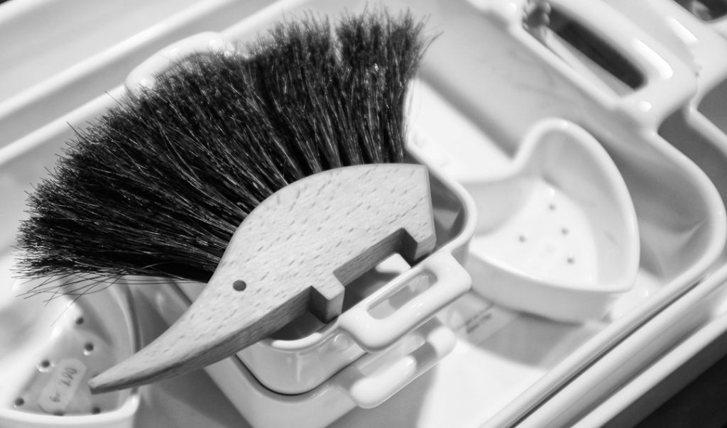 Household cleaning brush stored vertically in a small container