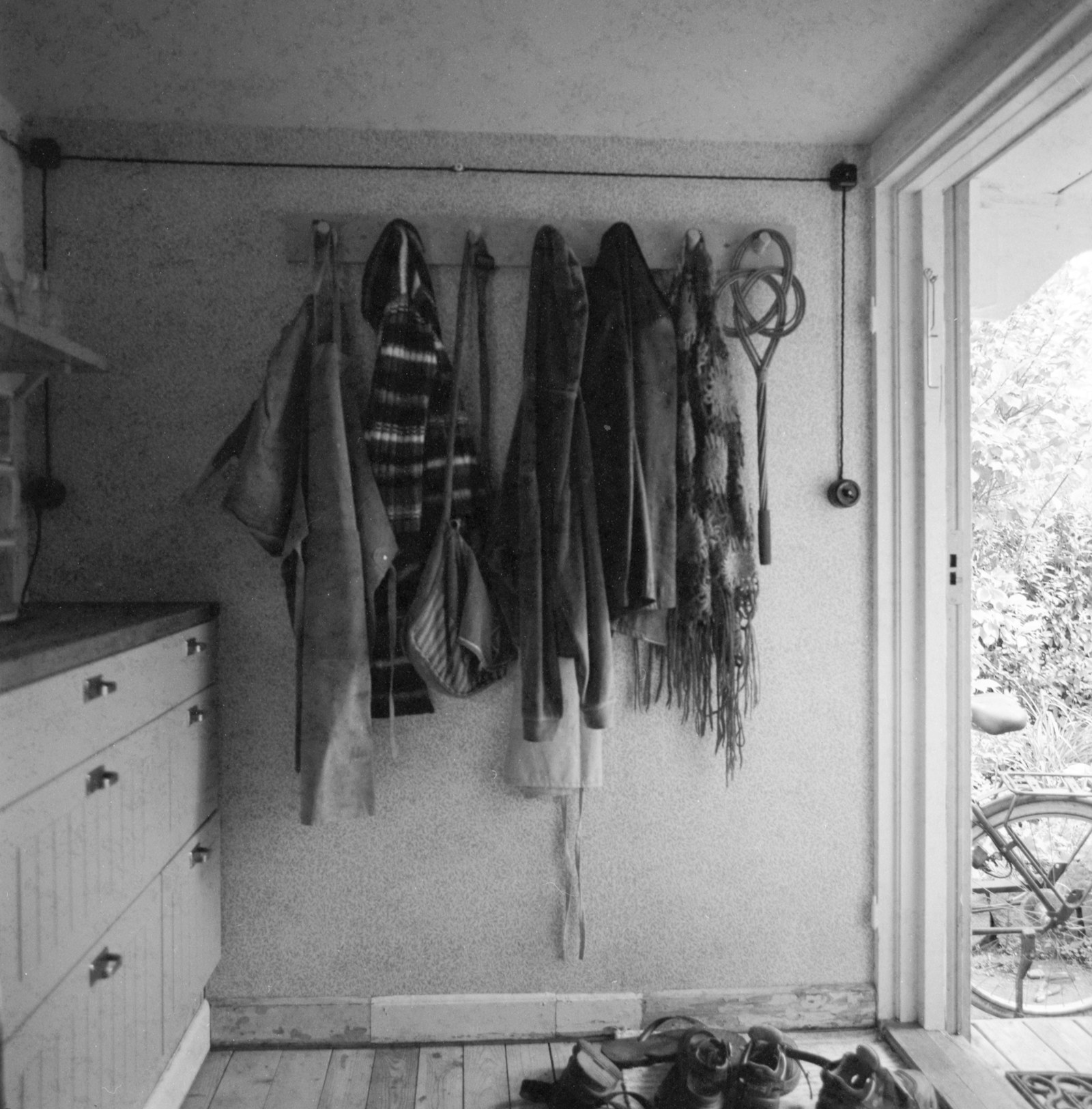 Coats hanging on a rack by an open doorway