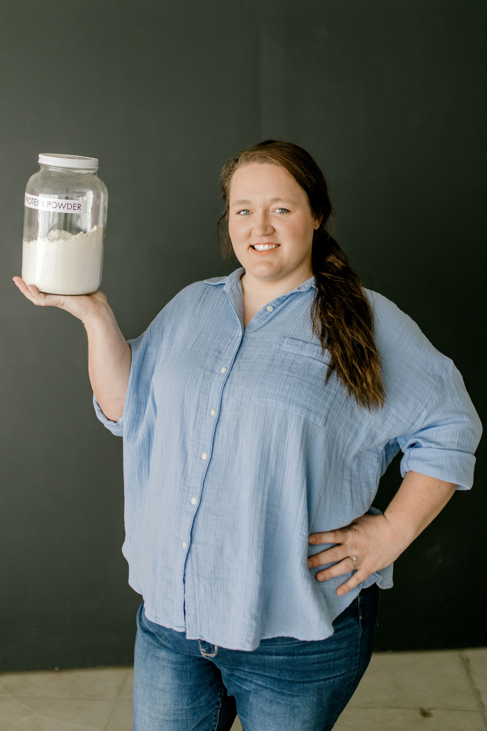 A smiling woman holds a jar of laundry powder