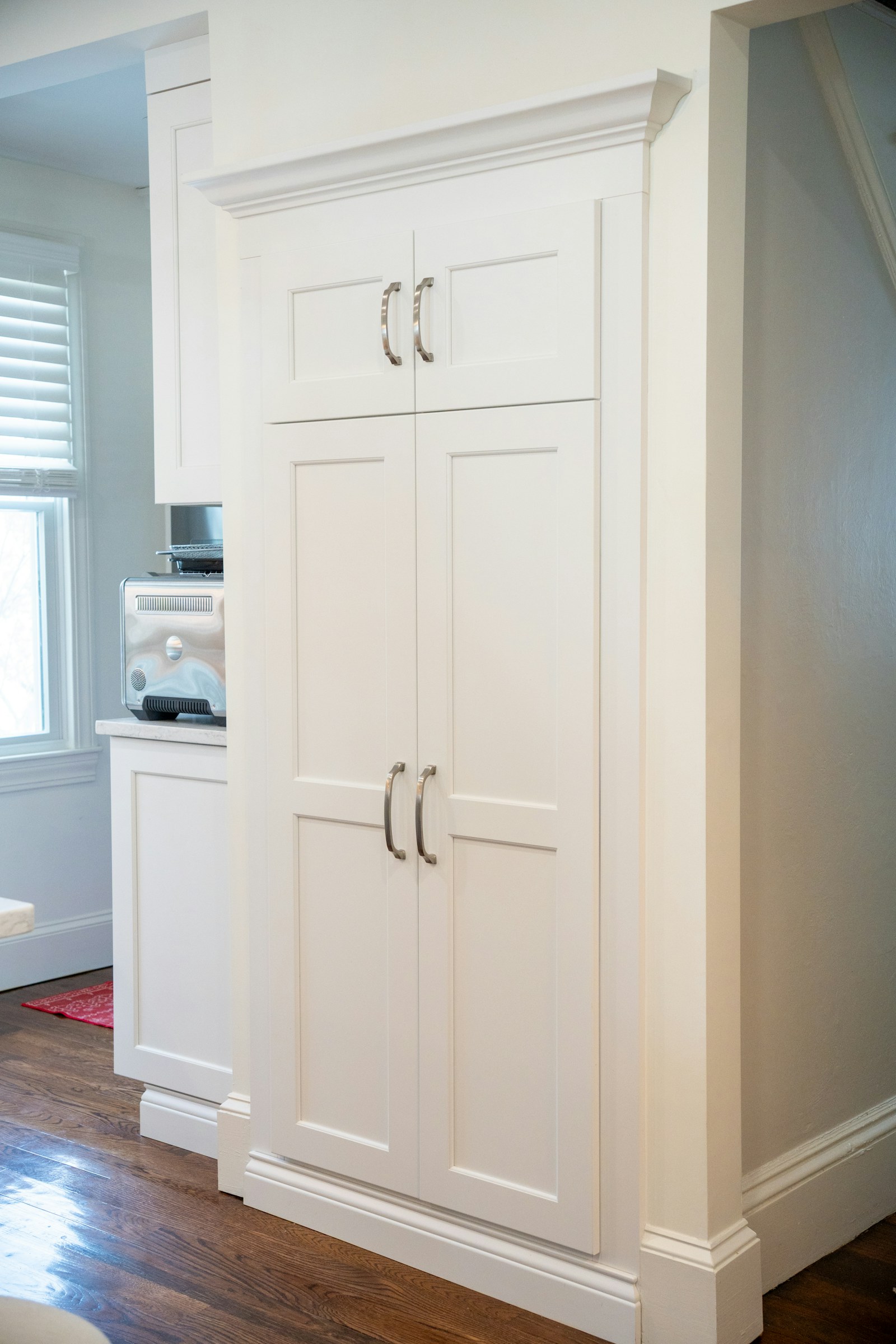 Tall white kitchen cabinets with silver handles in a bright home interior