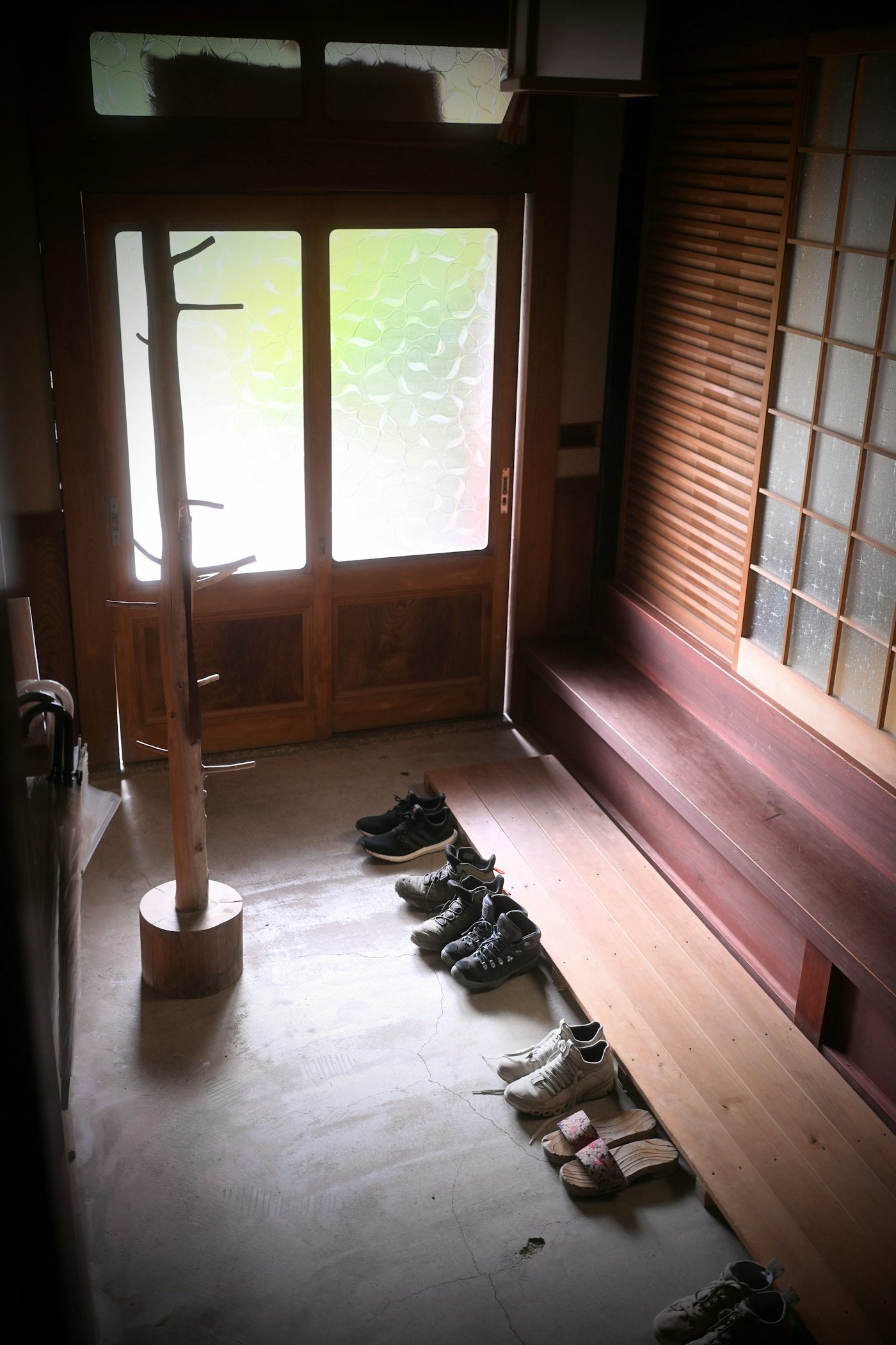 Several pairs of shoes lined up on a wooden step in a Japanese entryway