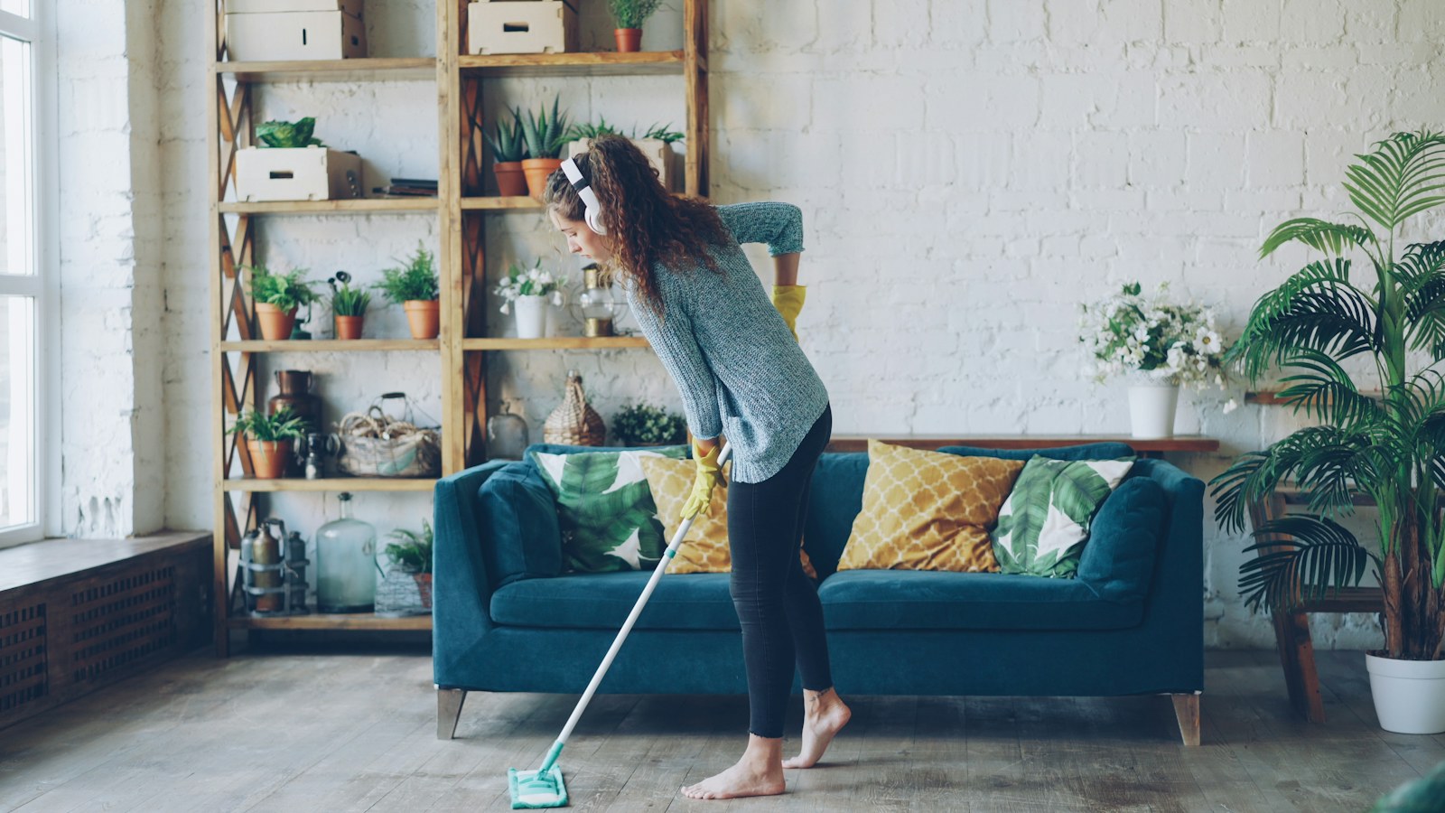 Woman mopping floor while wearing headphones