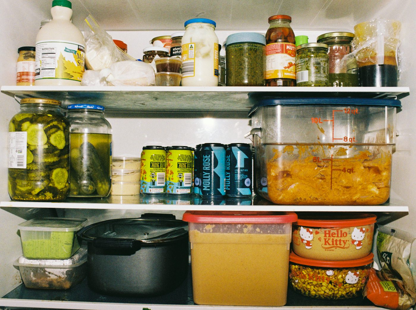Refrigerator shelves packed with jars, cans, and food containers
