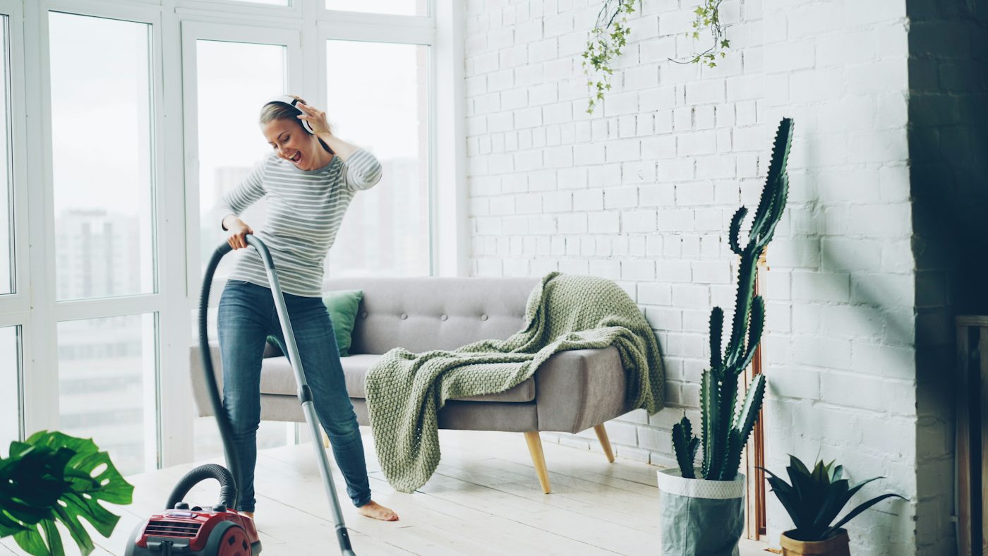 Woman happily vacuuming a bright, modern living room