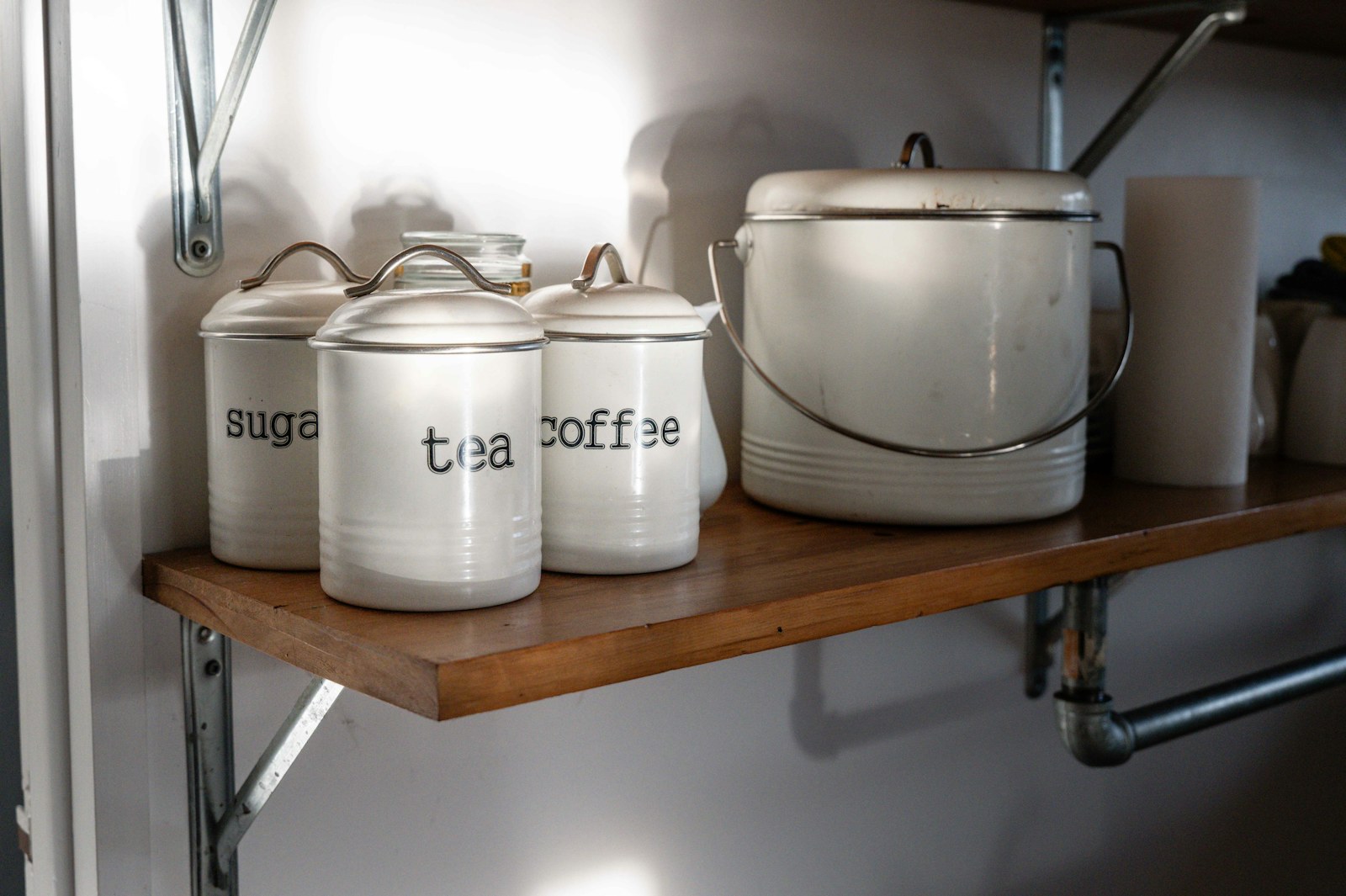 White canisters labeled sugar, tea, and coffee on shelf