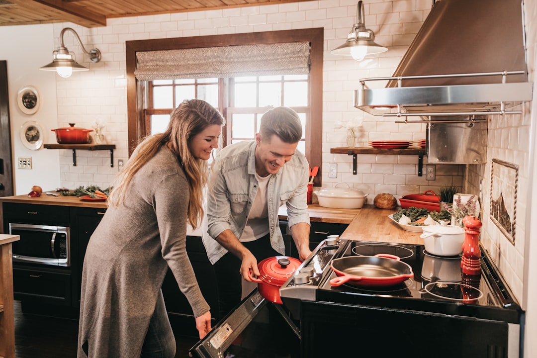 Two people cooking together in a compact kitchen where floor debris can accumulate