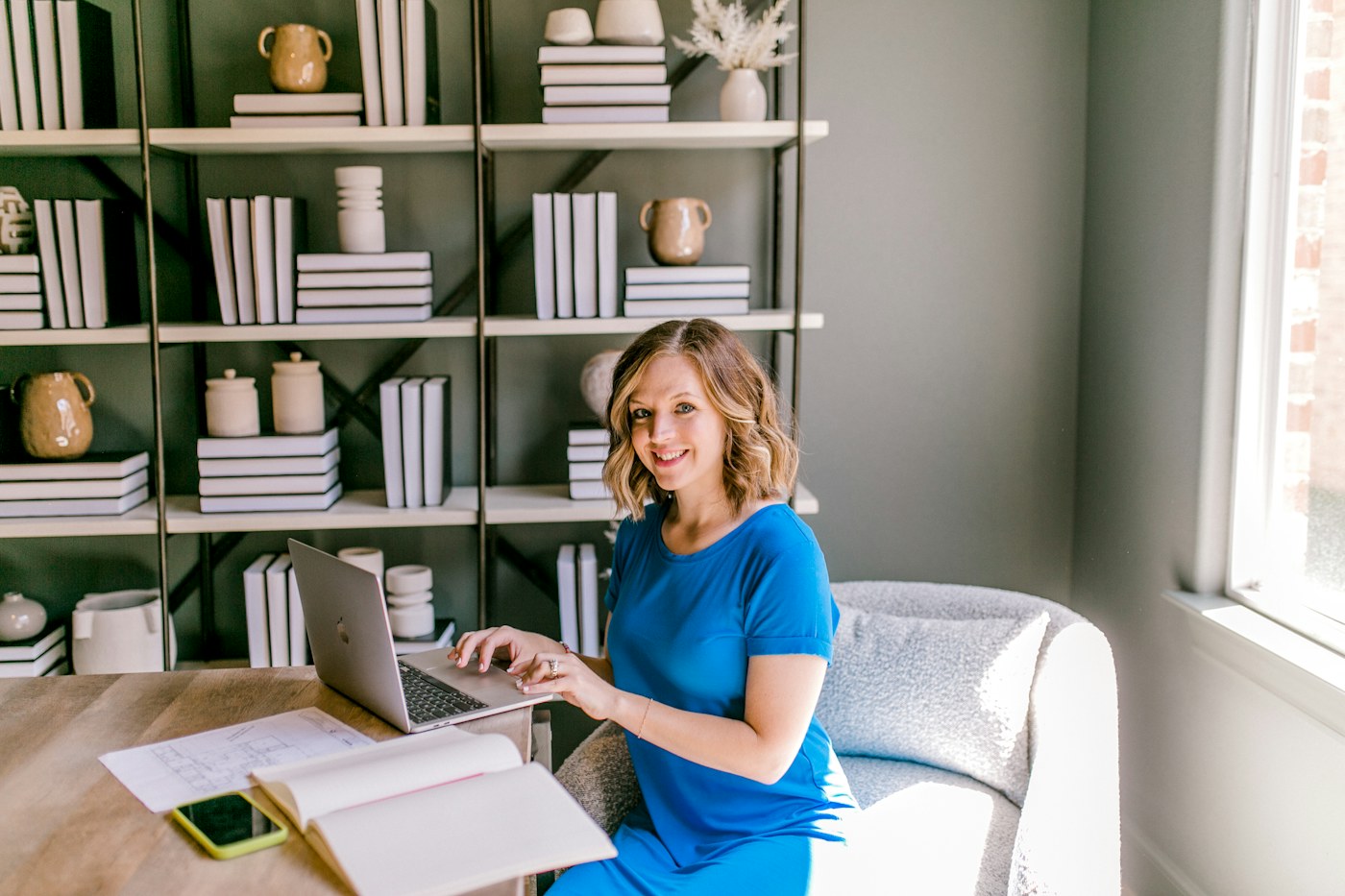 Person working at a home desk with nearby shelving