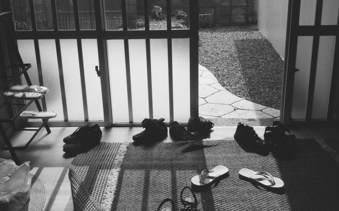 Footwear arranged on a mat near a sunny garden door