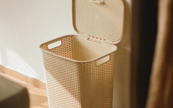 a white trash can sitting next to a white wall