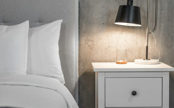 a bedroom with a bed, nightstand, and lamp