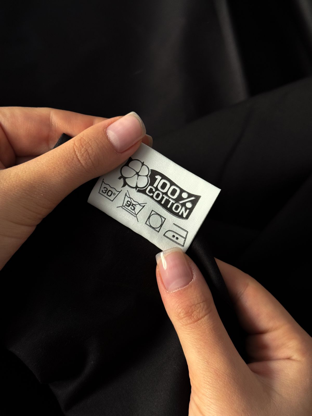 Hands holding a cotton fabric label