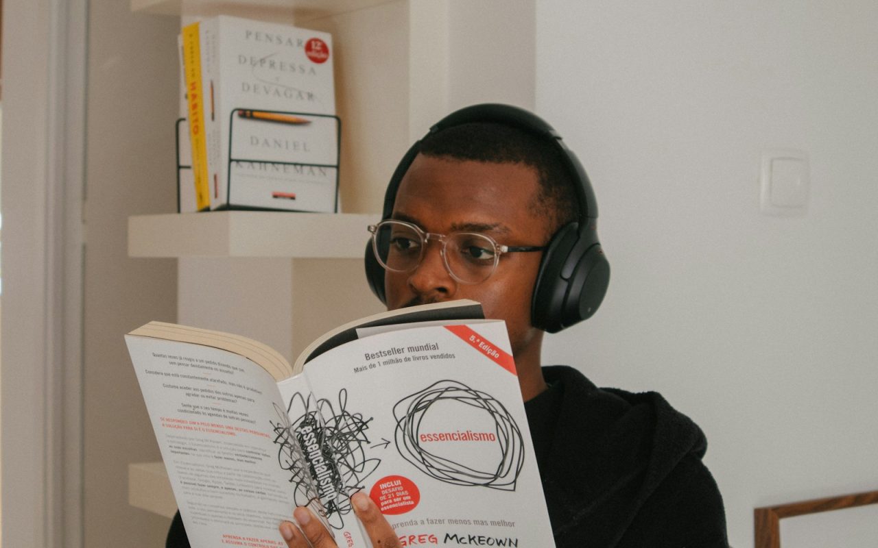 Person reading a book while wearing headphones