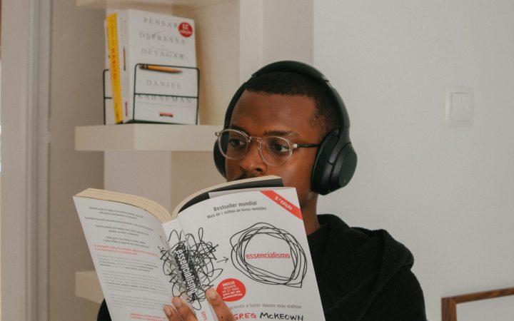 Person reading a book while wearing headphones