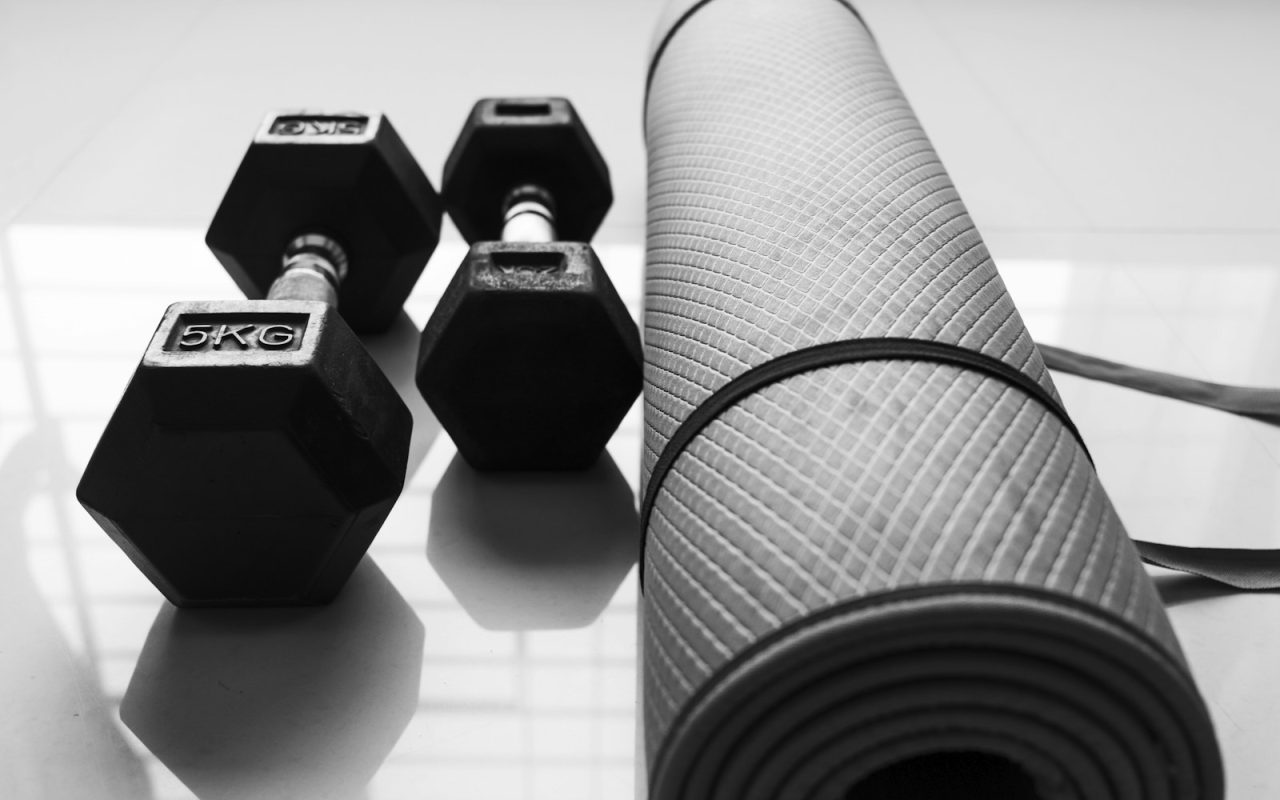 Dumbbells beside a rolled exercise mat