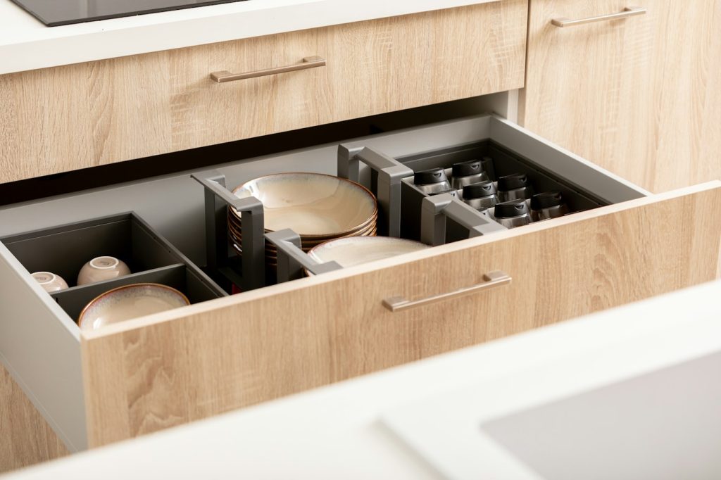 Kitchen drawer with plates, cups, and spices organized into visible sections