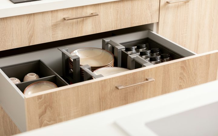 Kitchen drawer with plates, cups, and spices organized into visible sections