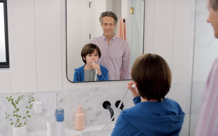 Adult using a bathroom sink and mirror in a compact shared bathroom