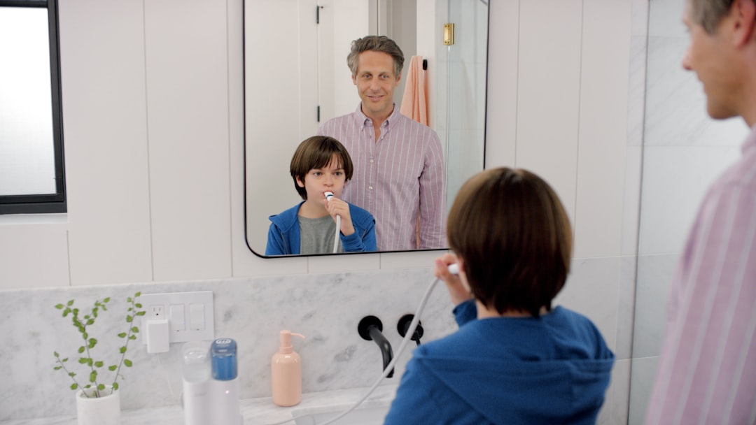 Adult using a bathroom sink and mirror in a compact shared bathroom