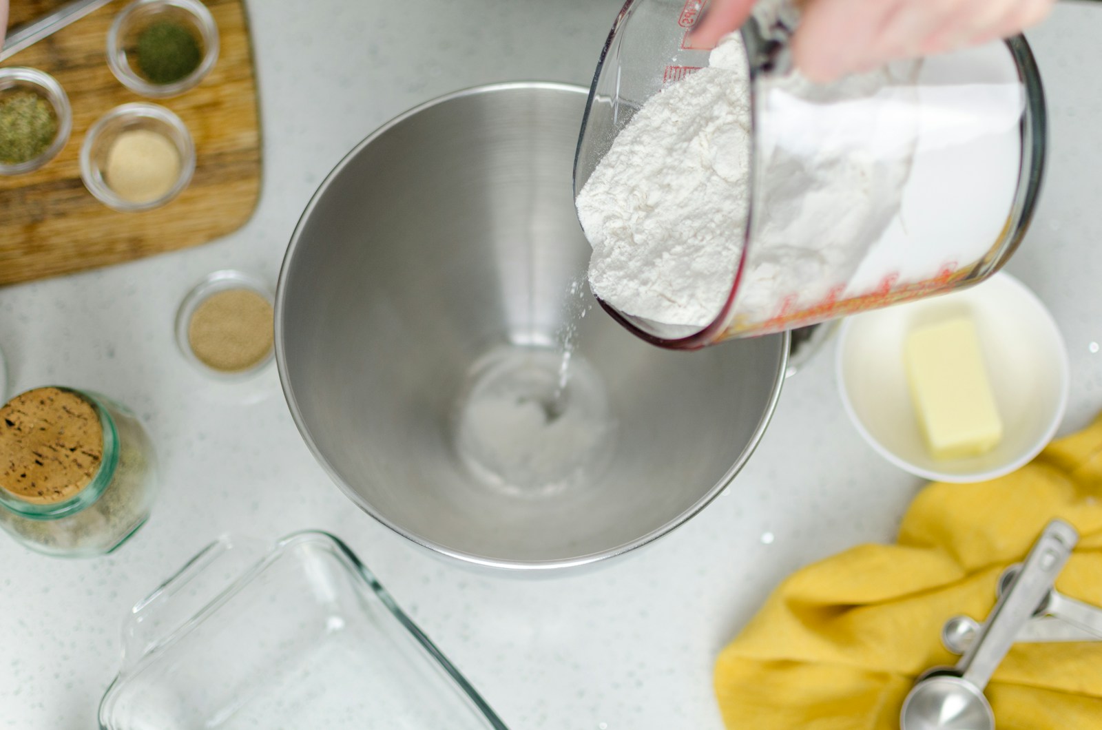 Flour being poured into a metal mixing bowl
