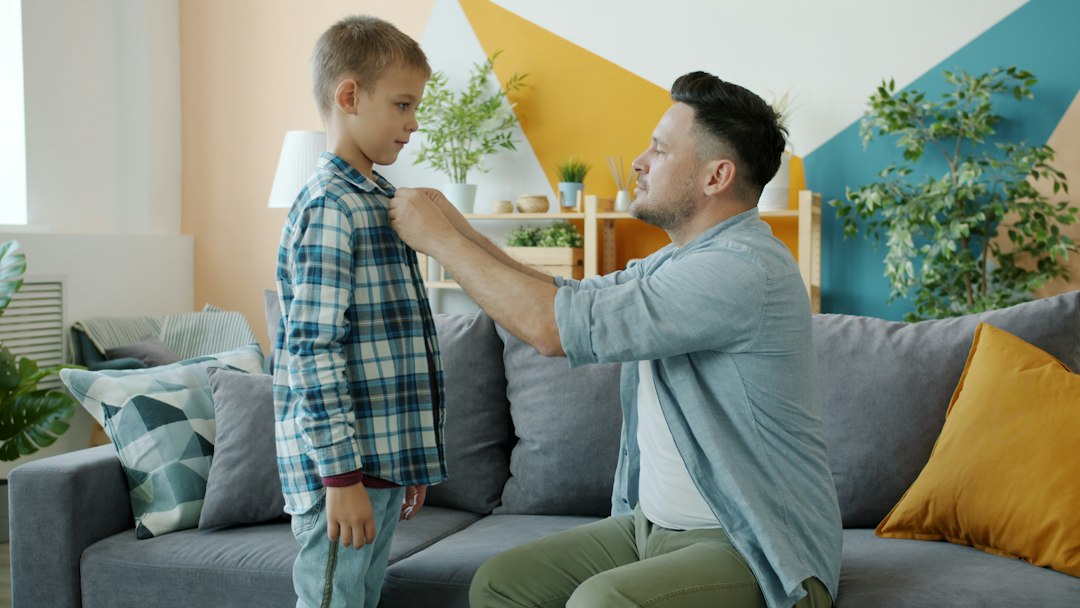Parent helping a child prepare clothing during the morning