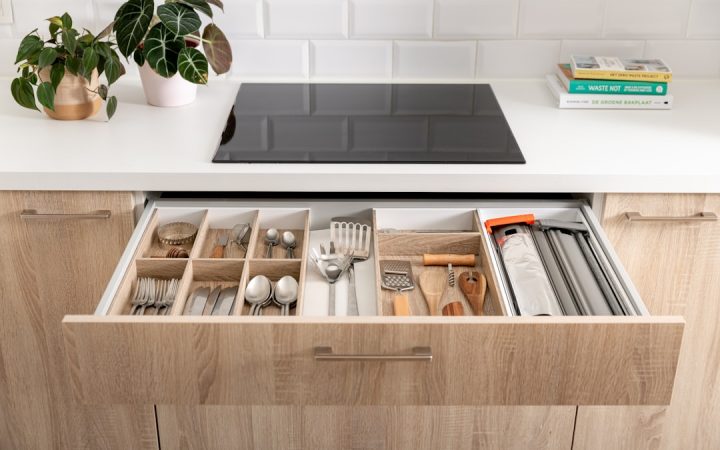 Organized kitchen drawer with wooden inserts creating clear category boundaries
