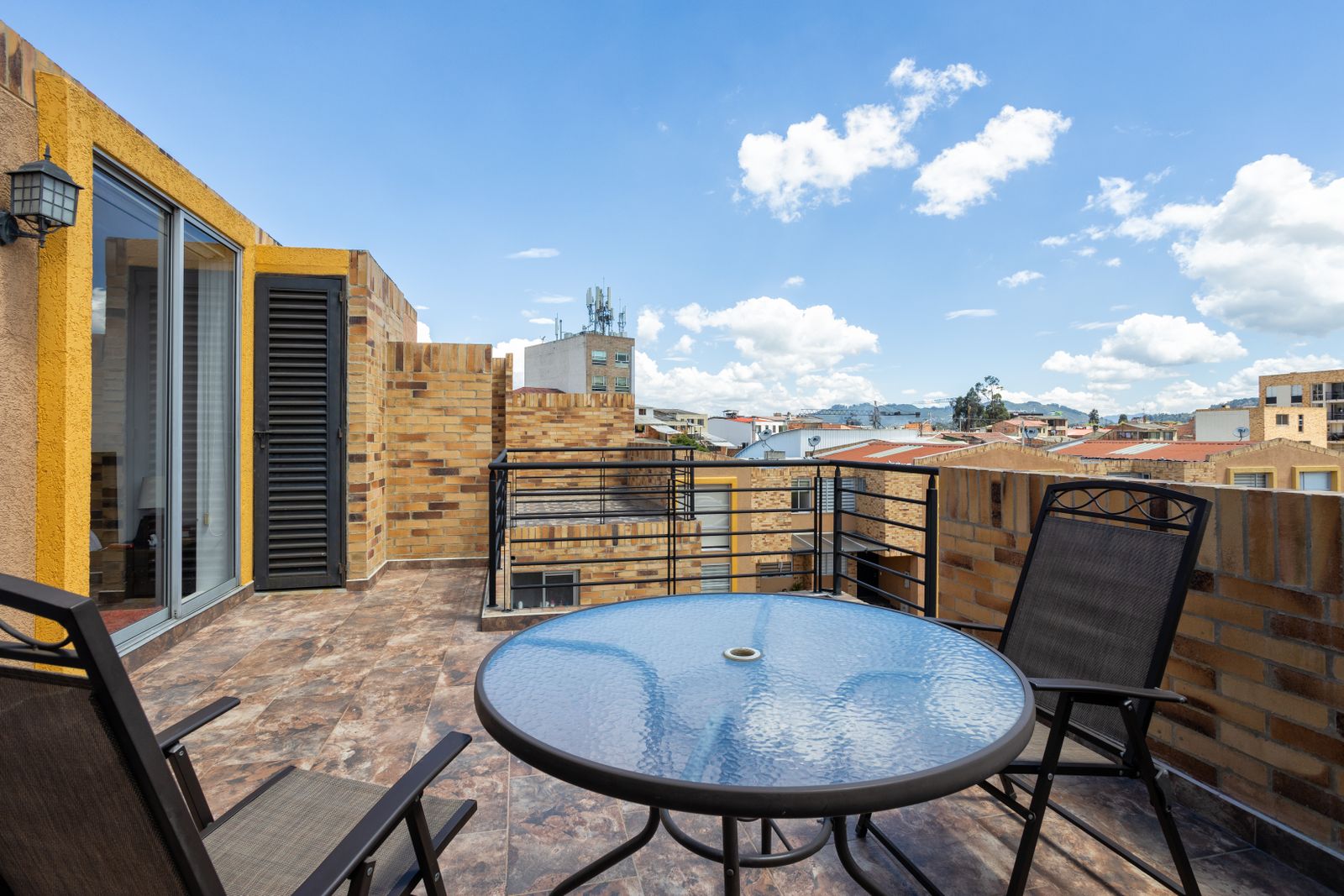 A round glass table and chairs on a city terrace
