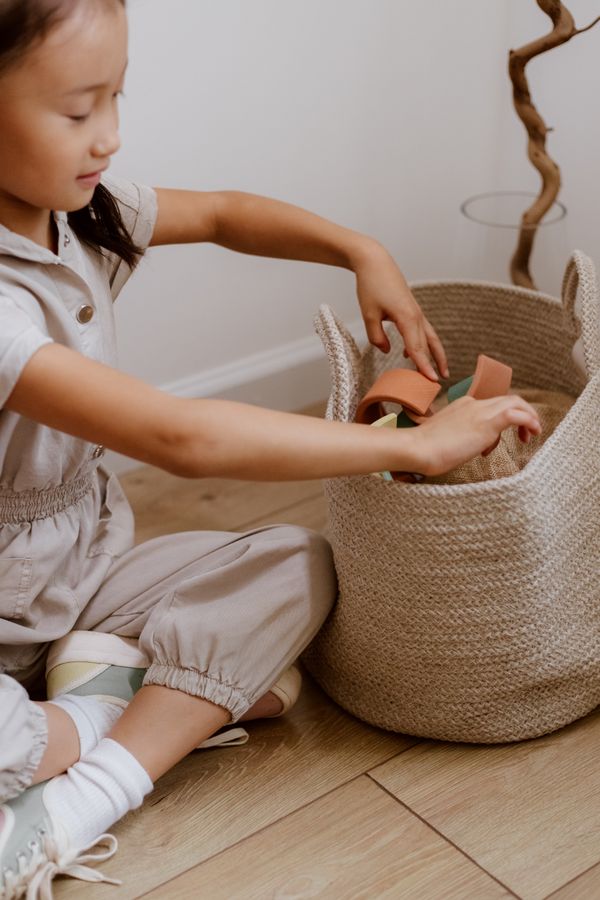Young child placing toys into a basket, illustrating simple rotation and reset routines