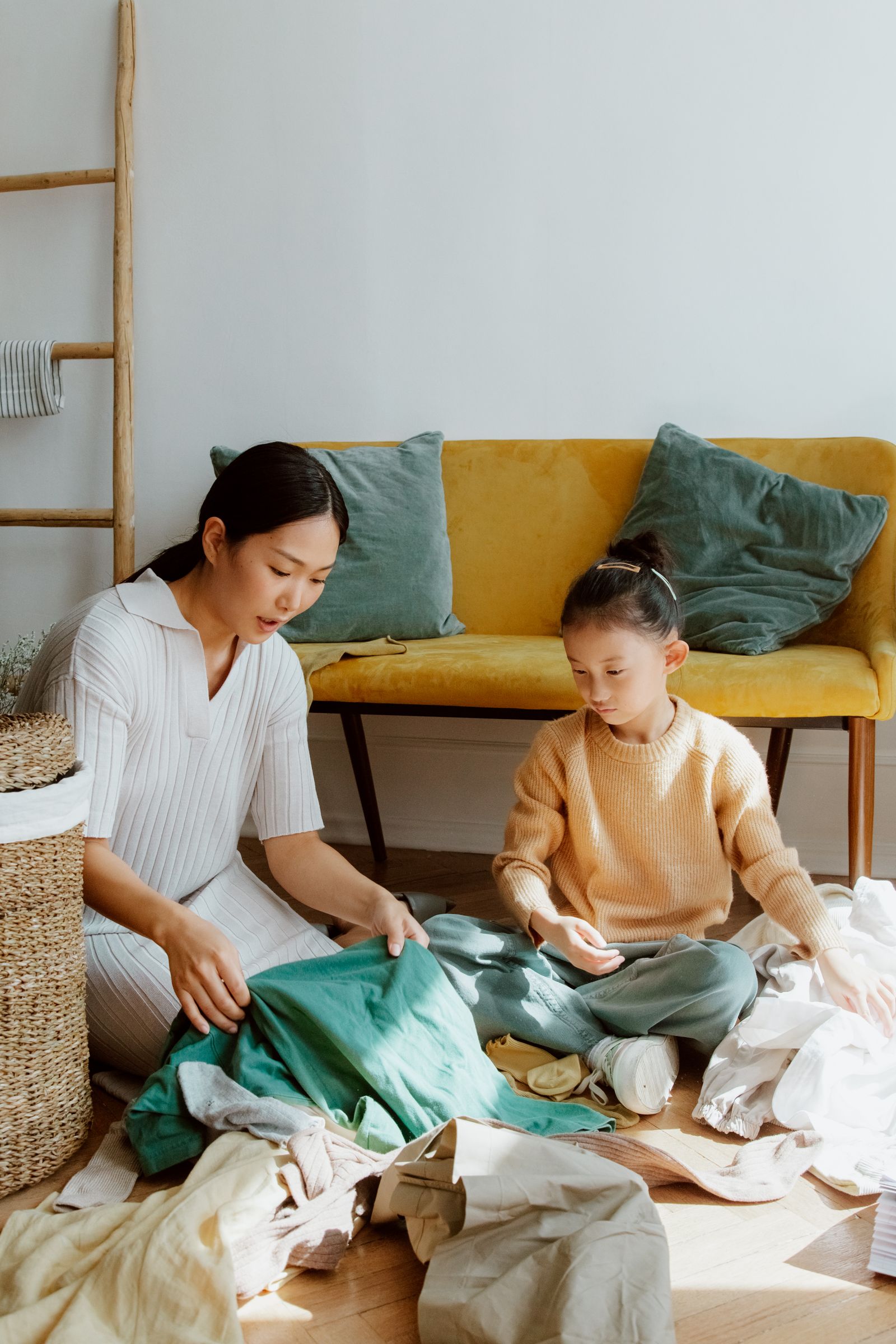 Mother and daughter sorting laundry together on the floor