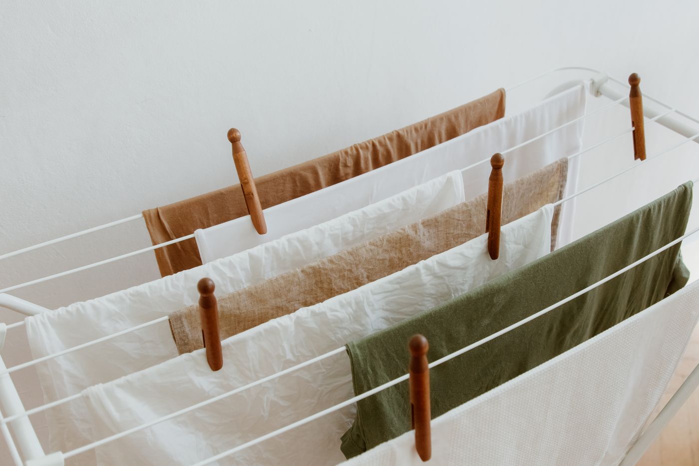 Light-colored laundry hanging neatly on a drying rack indoors