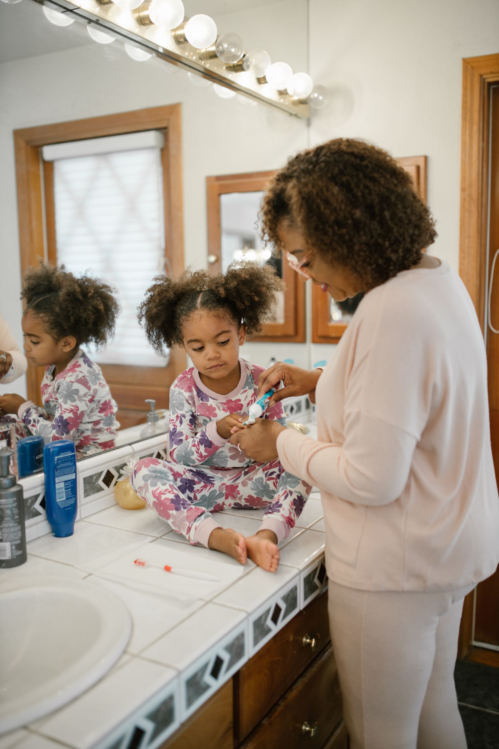 Mother helping a child with morning grooming in the bathroom