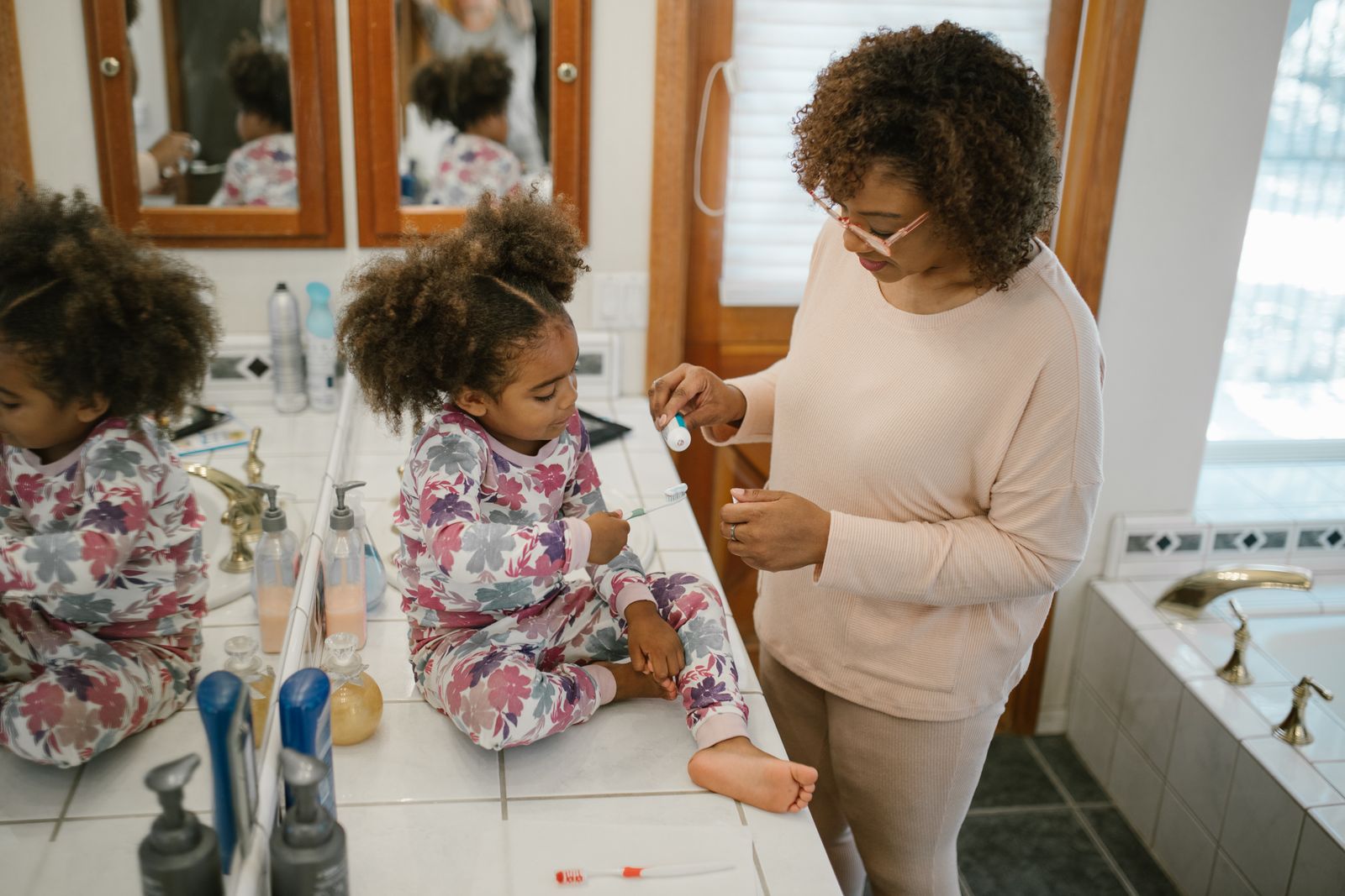 Parent helping a child brush teeth during a morning routine