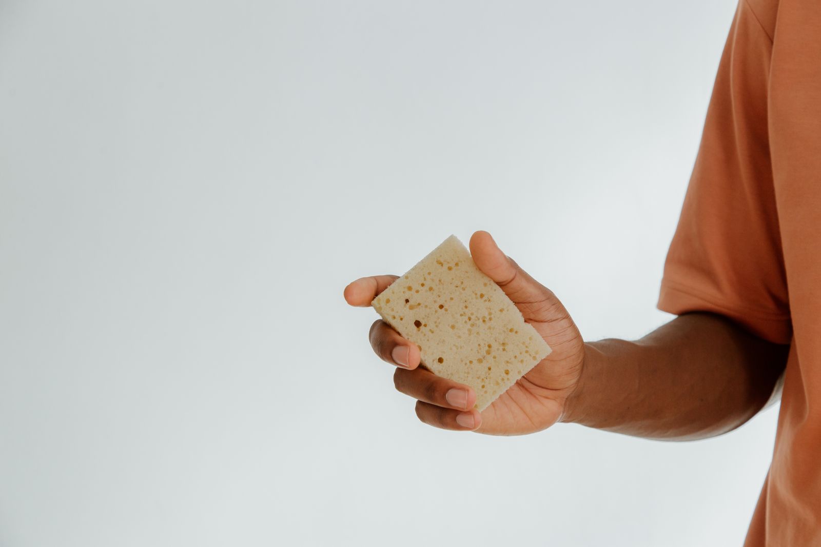 A hand holding a soft cleaning sponge