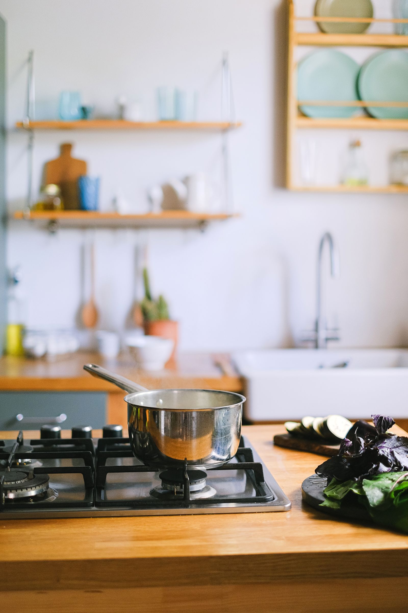 A cooking pot on a stove beside fresh vegetables