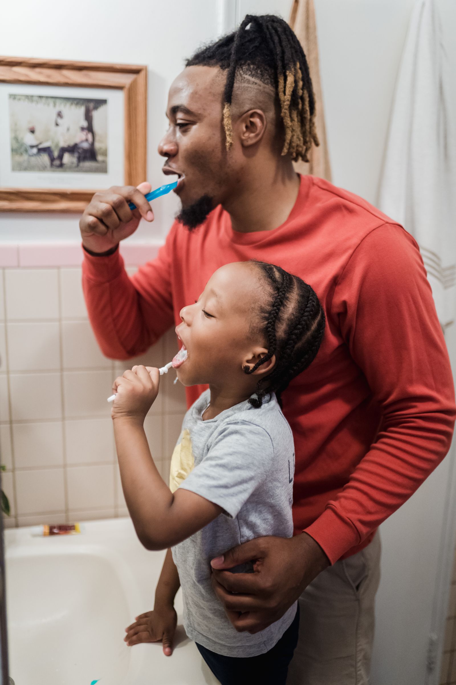 Father and daughter brushing their teeth together
