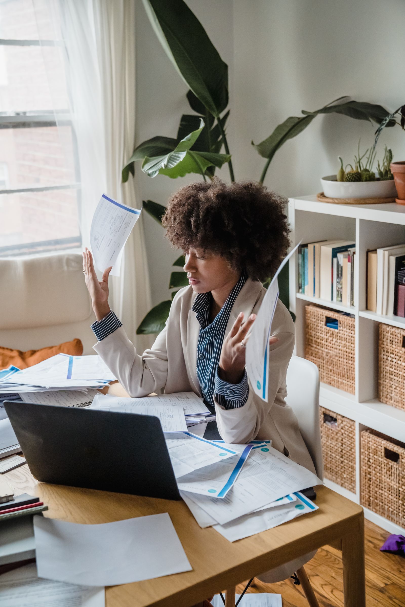 A woman comparing paper documents beside a laptop at home