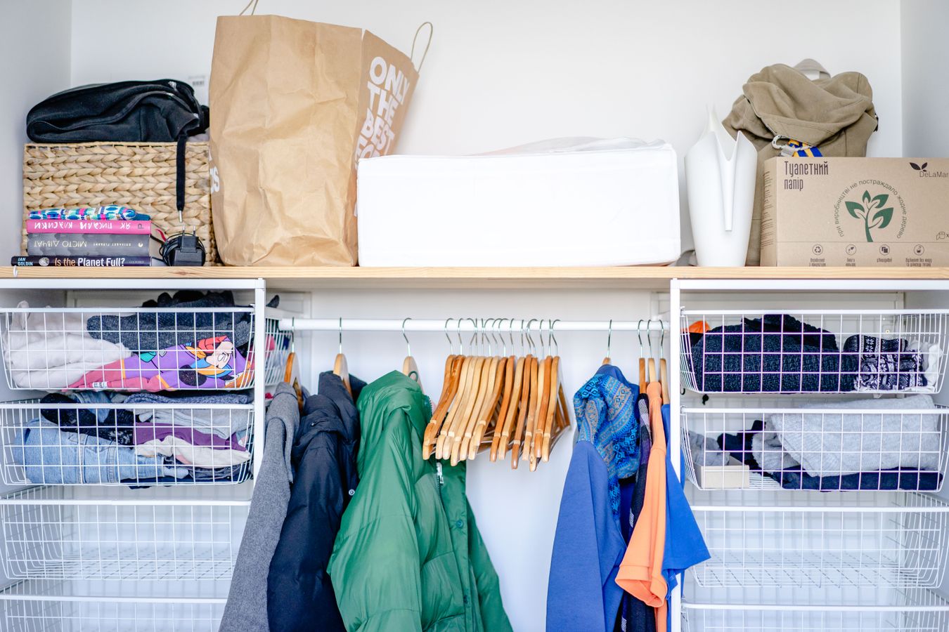 Minimal open wardrobe with hanging clothes, shelves, and storage baskets