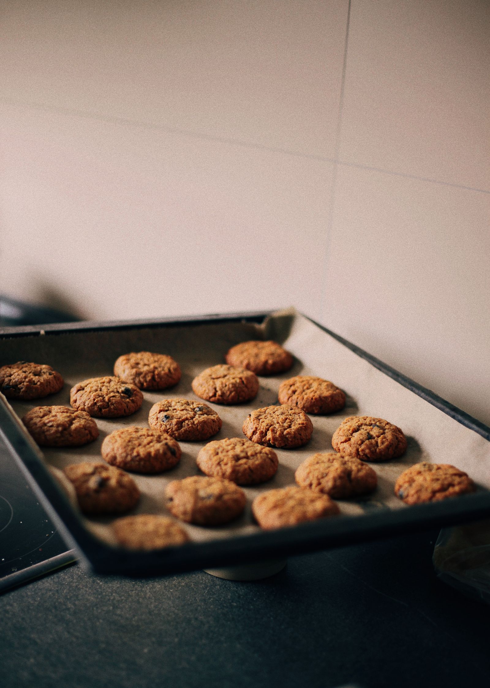Baked cookies resting on a dark rectangular baking sheet