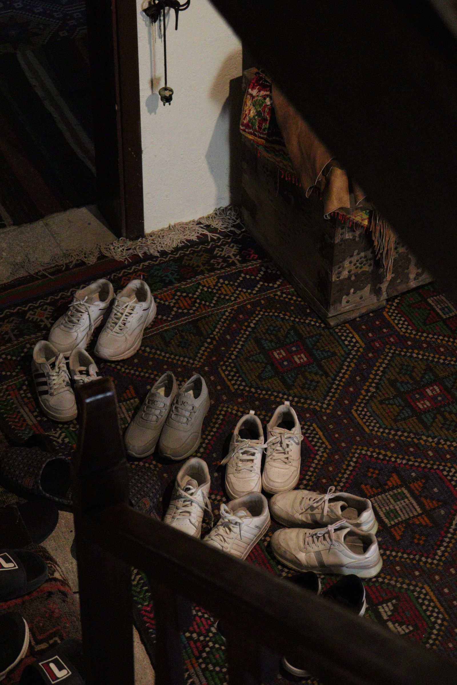 Several pairs of shoes resting on an indoor rug