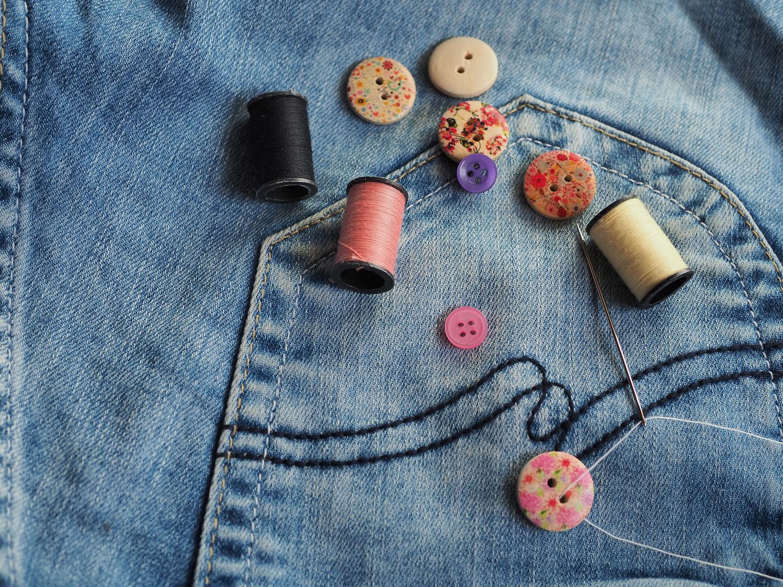 Buttons and thread spools arranged on denim