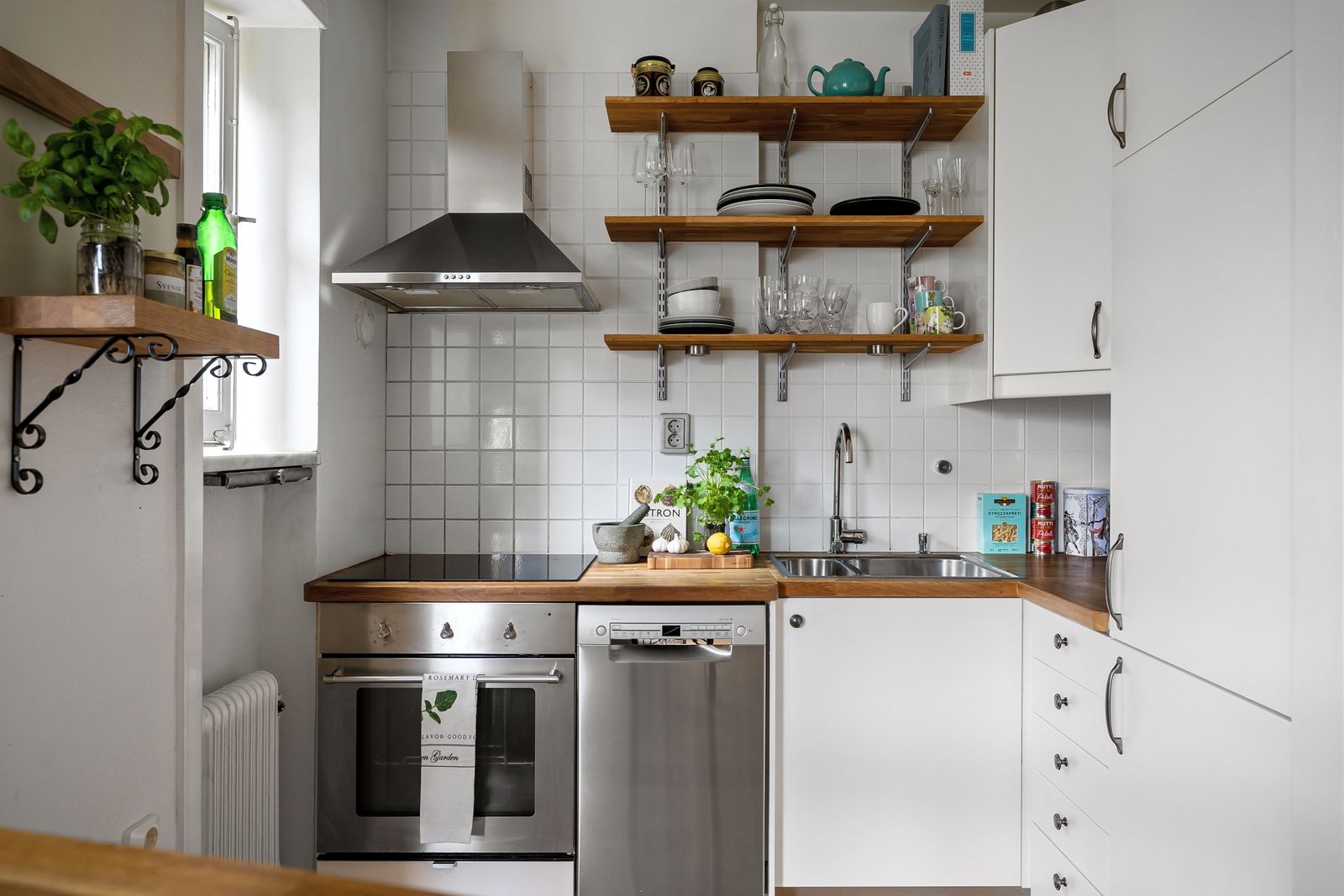 A compact white kitchen with open shelves and stainless steel appliances