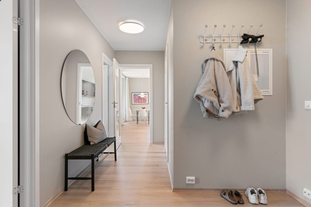 Small organized entryway with coats, shoes, a bench, and a clear walking path